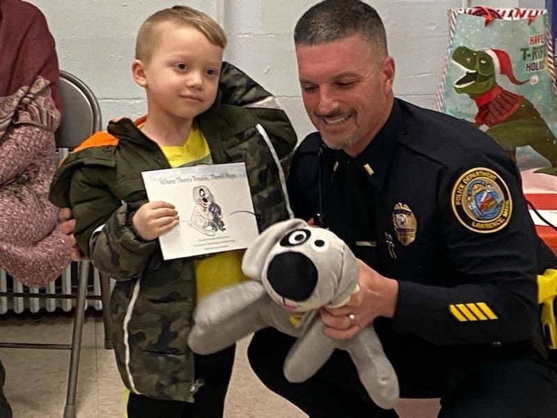 A Lawrence, MA police officer with Trouble the Dog and a child