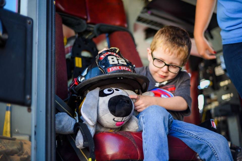 A boy hugging Trouble the Dog in a fire truck